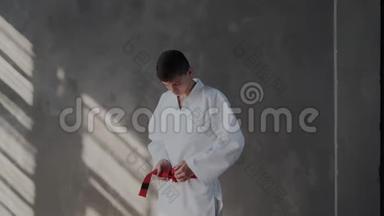 年轻的战士系着一条红色的腰带。 白和服，收了看镜头.. 这家伙正在<strong>打结</strong>，他会把